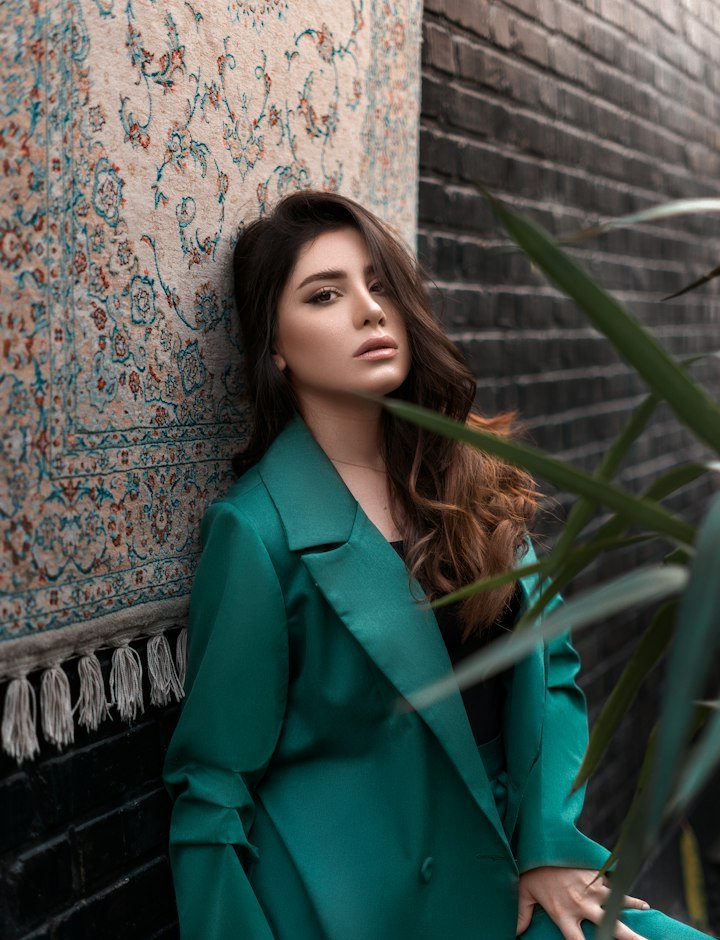 Model in a teal suit posing against a patterned wall on location